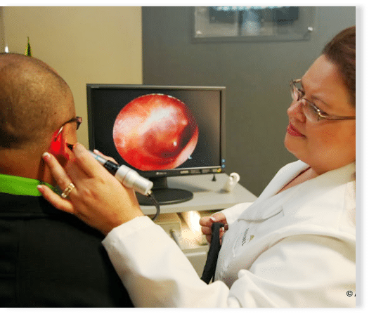 Audiologist examing a patient's ears for their hearing test