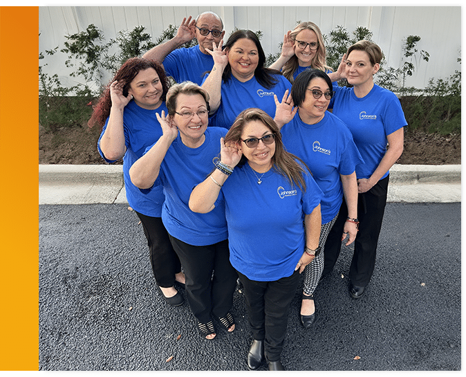 Group photo of the staff at Johnson's Hearing Center posing outside their office building in Inverness, FL